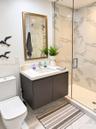 Wall-mounted vanity featuring a solid surface countertop, integrated sink, walk-in shower with floor-to-ceiling tile surround and glass enclosure, and