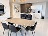 Contemporary kitchen featuring a center island with a solid surface countertop, high-gloss white cabinetry, integrated stainless steel double wall ove