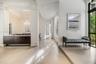 Interior space featuring large-format tile flooring, a dark-finish built-in console with a light-tone countertop, a crystal chandelier, arched archite