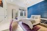 Bedroom featuring a deep blue textured accent wall, bay window, wood-finish flooring, recessed lighting, and a crystal chandelier