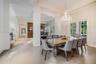 Spacious dining area featuring large-format tile flooring, tray ceilings, floor-to-ceiling columns, a crystal chandelier, and French door access to th