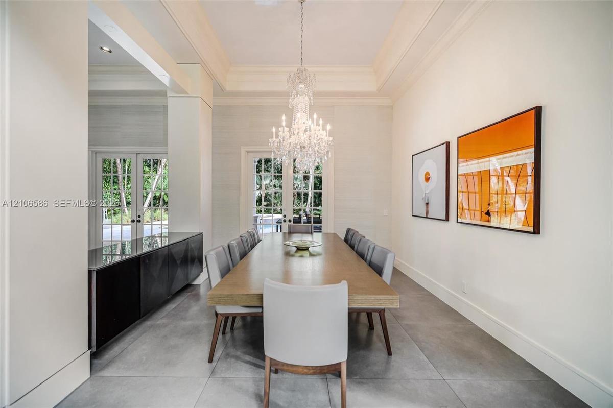 Formal room featuring a tray ceiling, crystal chandelier, large-format tile flooring, built-in cabinetry with a stone countertop, and multi-pane glass