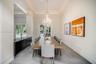 Formal room featuring a tray ceiling, crystal chandelier, large-format tile flooring, built-in cabinetry with a stone countertop, and multi-pane glass