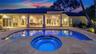 Covered patio featuring structural columns, inground pool, integrated spa, and stone-paver decking