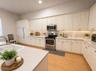 Kitchen featuring white cabinetry, solid-surface countertops, stainless steel appliances, and wood-finish flooring