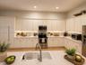 Kitchen featuring white shaker-style cabinetry, stainless steel appliances, under-cabinet lighting, a farmhouse-style sink with a pull-down faucet, an
