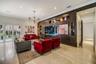 Custom wood-veneer accent wall featuring integrated recessed shelving, multi-arm geometric chandelier, light-toned flooring, and floor-to-ceiling glas