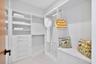 Completing the suite is its private custom-fitted dressing room, beautifully organized with extensive built-in shelving, drawers, hanging space and a 