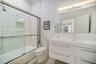 Modern bathroom featuring a high-gloss double vanity with an integrated countertop, large-format tiled walls with decorative inlay, built-in shower ni