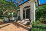 Covered entryway featuring white brick pillars, a multi-paneled dark wood front door with arched transom, tiered concrete steps, and a herringbone-pat