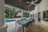 Covered patio featuring stone-tile flooring, a wood-paneled ceiling, ceiling fans, and structural columns