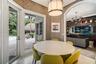 Dining area featuring textured wall coverings, stone-finish flooring, a contemporary drum pendant light, and French doors opening to an exterior patio