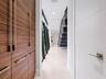 Hallway featuring wood-finish cabinetry with vertical hardware, large-format tile flooring, recessed ceiling lighting, and a dark-toned staircase with