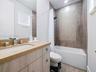 Modern bathroom vanity featuring light wood-finish cabinetry, a rectangular undermount sink, and a countertop with integrated backsplash