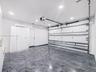 Garage featuring high-gloss epoxy flooring, built-in white cabinetry, recessed LED lighting, and a climate control unit