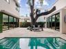 Courtyard featuring natural stone hardscaping, an inground pool with built-in stairs, multi-panel sliding glass doors, and a mature tree