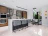 Modern kitchen featuring horizontal-grain wood cabinetry, a central island with a waterfall-edge countertop, built-in double wall ovens, recessed ligh