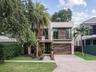 Contemporary two-story exterior featuring smooth stucco siding with wood-tone accents, a stone-paved driveway, a second-story balcony with metal raili