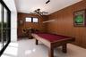 Wood-paneled walls, large-format tile flooring, multi-light modern chandelier, horizontal linear pendant light, and black-framed sliding glass doors