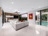 Large-format tile flooring, wood-panel accent wall with integrated built-in cabinetry, recessed ceiling lighting, statement multi-arm chandelier, and 