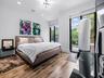 Wood-finish flooring, recessed lighting, modern multi-arm ceiling fixture, and floor-to-ceiling glass sliding doors opening to an outdoor balcony