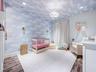 Room featuring cloud-patterned wallpaper extending to the ceiling, wood-finish flooring, dual wall-mounted brass light fixtures, recessed ceiling ligh