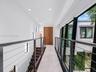 Hallway featuring tile flooring, recessed ceiling lighting, a wood-finish double door, and a cable railing system with a dark metal frame