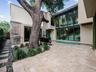 Modern courtyard featuring stone paver flooring, floor-to-ceiling glass windows, a built-in outdoor grill, a mature tree, and a linear swimming pool