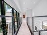 Hallway featuring polished light-toned flooring, recessed ceiling lighting, and a metal cable railing system with dark-finish posts, complemented by f