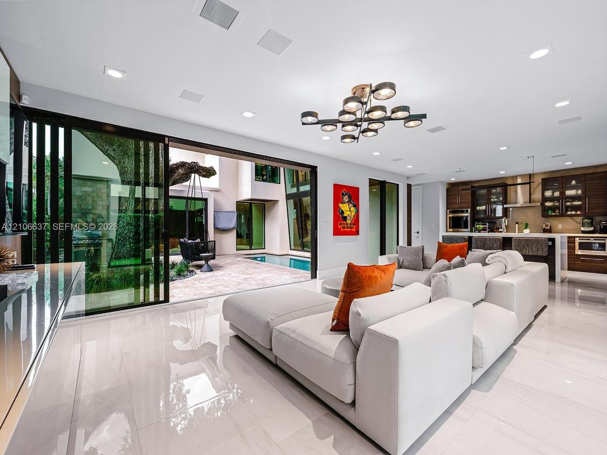 Open-concept interior featuring large-format polished tile flooring, recessed ceiling lighting, a contemporary multi-arm chandelier, and floor-to-ceil