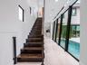 Staircase with dark wood-finish treads and metal railings, large-format tile flooring, recessed ceiling lighting, and floor-to-ceiling black-framed wi