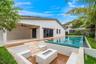 Covered outdoor patio with stone flooring, custom zero-edge pool, integrated stone fire feature, and tiered stone steps leading to a wood-finish deck
