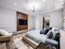 Tray ceiling with recessed lighting, central multi-arm modern light fixture, wood-finish media wall with stone hearth, and floor-to-ceiling mirror