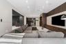 Vaulted ceiling featuring recessed lighting, stone-finish accent wall with integrated media storage, and custom floor-to-ceiling wood slat paneling