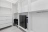 Walk-in closet featuring white built-in shelving, integrated hanging rods, and a stack of four pull-out drawers