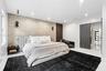 Textured stone accent wall, wood-slat feature paneling, recessed ceiling lighting, wall-mounted spherical light fixtures, and oversized dark-finish do