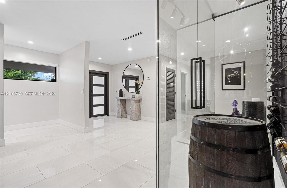 Entryway featuring large-format light tile flooring, recessed ceiling lighting, a dark-framed multi-panel front door, and a climate-controlled glass-e