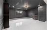 Interior space featuring charcoal-toned wall paneling, large-format polished tile flooring, a built-in wood-finish wet bar, and a multi-light flush-mo