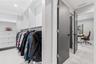 Custom walk-in closet featuring white built-in shelving, integrated storage drawers, and contemporary charcoal-toned interior doors with matte black h