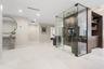 Glass-enclosed temperature-controlled wine display with wall-mounted racking, large-format tile flooring, recessed ceiling lighting, and built-in dark