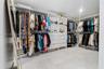 Walk-in closet featuring extensive built-in white shelving, integrated drawers, full-length hanging rods, and large-format porcelain tile flooring