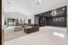 Vaulted ceilings with recessed lighting, large-format polished tile flooring, wall panel molding, and multi-panel sliding glass doors