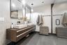 Floating wood-finish double vanity featuring white vessel sinks, matte black wall-mounted faucets, rectangular mirrors, and large-format tile flooring