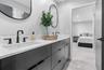 Double vanity with charcoal-toned cabinetry, light-toned stone-surface countertop, dual rectangular undermount sinks, matte black plumbing fixtures, a