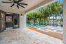 Covered patio featuring stone tile flooring and a ceiling fan, wood-finish decking, sunken seating area with a built-in fire feature, and an infinity-