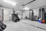 Garage featuring large-format tile flooring, built-in light grey cabinetry, a subway tile backsplash, and overhead fluorescent lighting