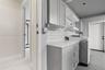 Laundry space featuring shaker-style grey cabinetry, white solid-surface countertop, white subway tile backsplash, and floating wall shelves