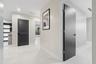Interior hallway featuring polished large-format tile flooring, matte black lever hardware, a louvered charcoal-finished door, and a multi-panel charc