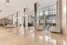 Expansive lobby featuring polished stone flooring, floor-to-ceiling glass walls, decorative chandeliers, and full-height stone-clad columns