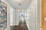 Hallway featuring dark wood-finish flooring, crisp white walls, and multiple solid-core interior doors with satin nickel hardware